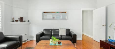 A living room with a black leather sofa, a wooden coffee table, and a fireplace.