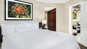 Ein Hotelzimmer mit einem großen Bett, einem Nachttisch, einem gerahmten Bild, einem Kleiderschrank und einem durch eine offene Tür einsehbaren Badezimmer.