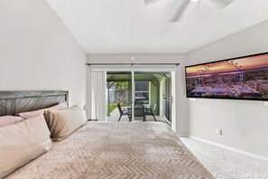 A bedroom with a bed, a TV on the wall, and a balcony with a view of a Ferris wheel. - Sunny 4BR Davenport Lakes House w/ Pool & Lake Access (Davenport)