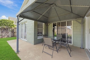 A covered patio area with a table and chairs, a sliding glass door, and a view of a backyard. - Sunny 4BR Davenport Lakes House w/ Pool & Lake Access (Davenport)
