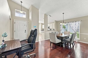 A dining area with a table and chairs, a kitchen in the background, and a view through the window. - Sunny 4BR Davenport Lakes House w/ Pool & Lake Access (Davenport)