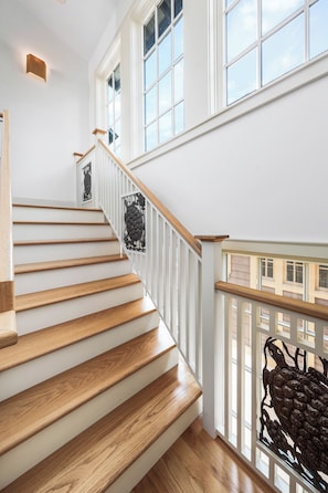A staircase with wooden steps and white railings, leading to a balcony with a metal railing. - Saltwater & Shutters Cottage - Rosemary Beach - 4 Free Bikes! (Rosemary Beach)