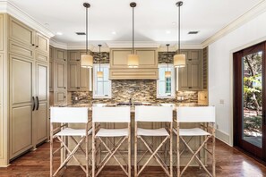 A kitchen with a central island, pendant lighting, and a view of the outdoors. - Saltwater & Shutters Cottage - Rosemary Beach - 4 Free Bikes! (Rosemary Beach)