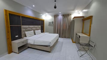 Un dormitorio con cama, mesitas de noche, un espejo y un perchero para toallas.