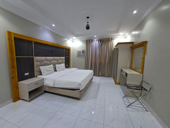 A bedroom with a bed, nightstands, a mirror, and a hanging towel rack. - Rahti Star 2 Serviced Apartments (Taif)