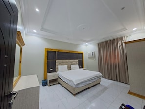 A hotel room with a bed, a nightstand, a wardrobe, and a window with curtains. - Rahti Star 2 Serviced Apartments (taif)