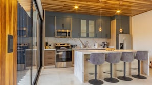 A modern kitchen with a central island, bar stools, and stainless steel appliances. - Casa Amarí: Private Pool, Rooftop Terrace and Three Ensuite Bedrooms (La Fortuna)