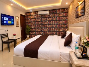 Habitación de hotel con una cama grande, televisión de pantalla plana, estantería y un cuadro en la pared.