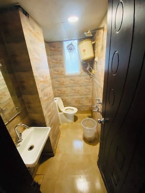 A bathroom with a toilet, sink, and a water heater. - Hotel silver stay delhi  (New Delhi)