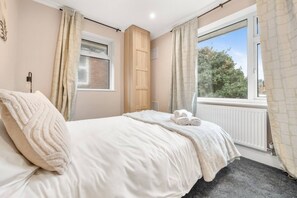 A bedroom with a bed, a window, a radiator, and a door. - Lovely Ealing 3-bed in Greater London (London)