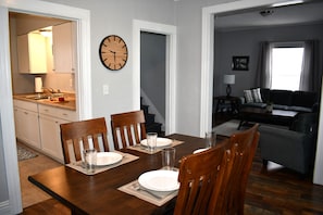 A dining area with a wooden table, four chairs, and a wall clock. - A Relaxing Getaway on Grant in Geneva. (Geneva)