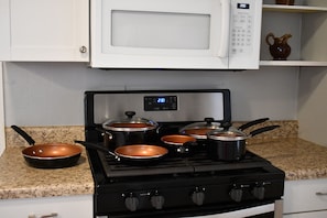 A kitchen with a gas stove, pots, a microwave, and granite countertops. - A Relaxing Getaway on Grant in Geneva. (Geneva)