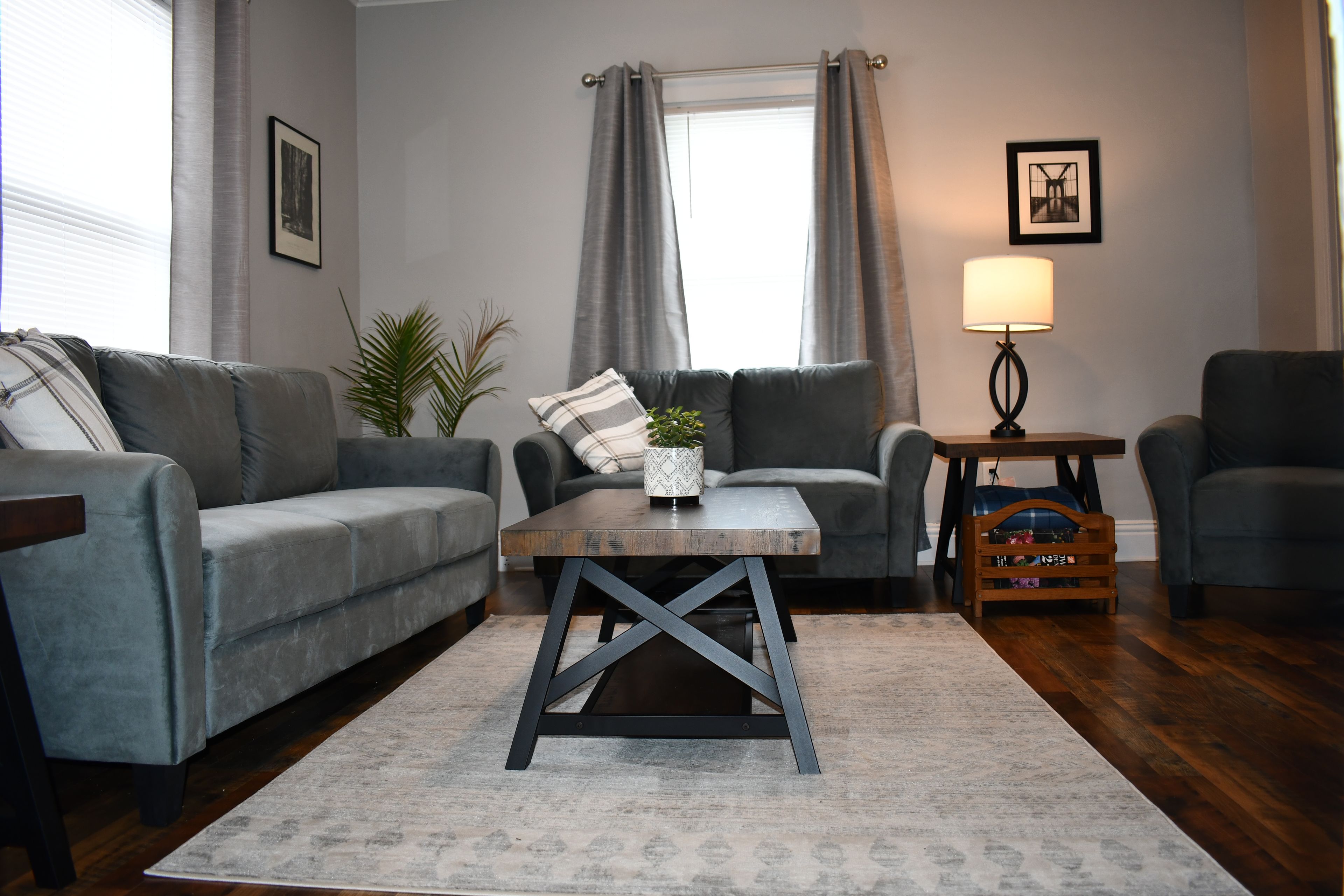 Ein Wohnzimmer mit zwei grauen Sofas, einem Couchtisch, einer Lampe und einem kleinen Holznachttisch.