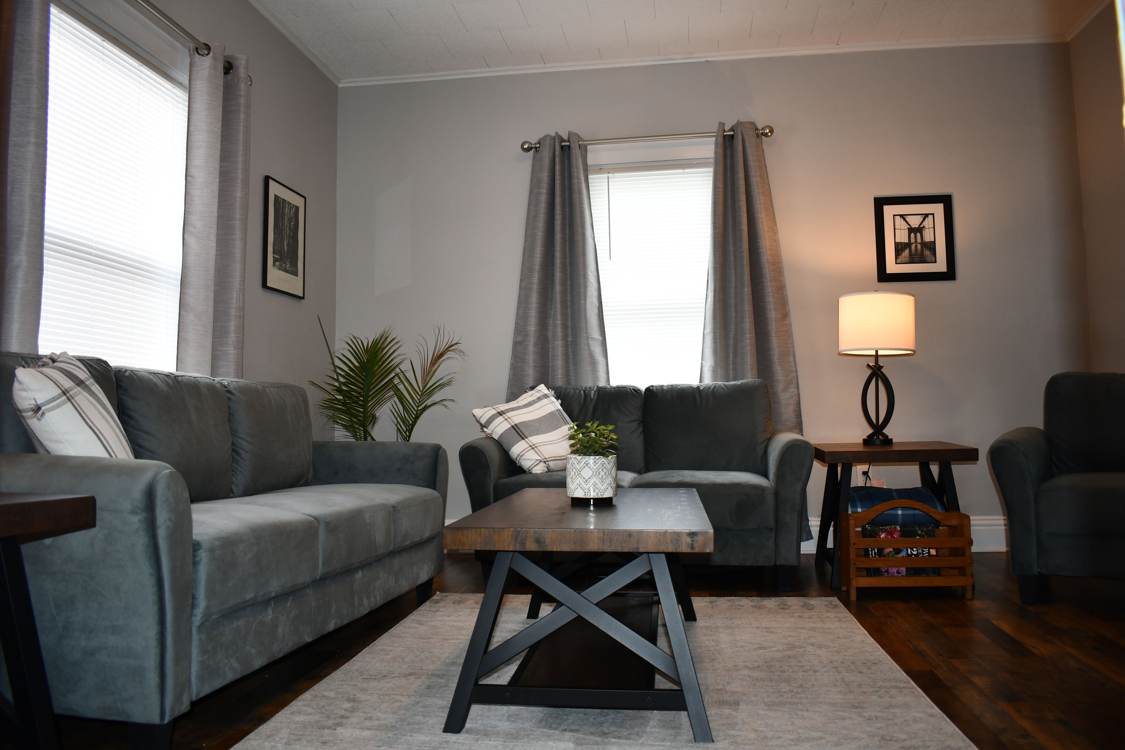A living room with two grey sofas, a wooden coffee table, a lamp, and a small side table.