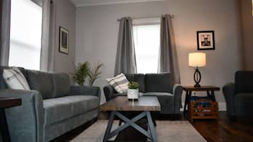 A living room with two grey sofas, a wooden coffee table, a lamp, and a small side table.
