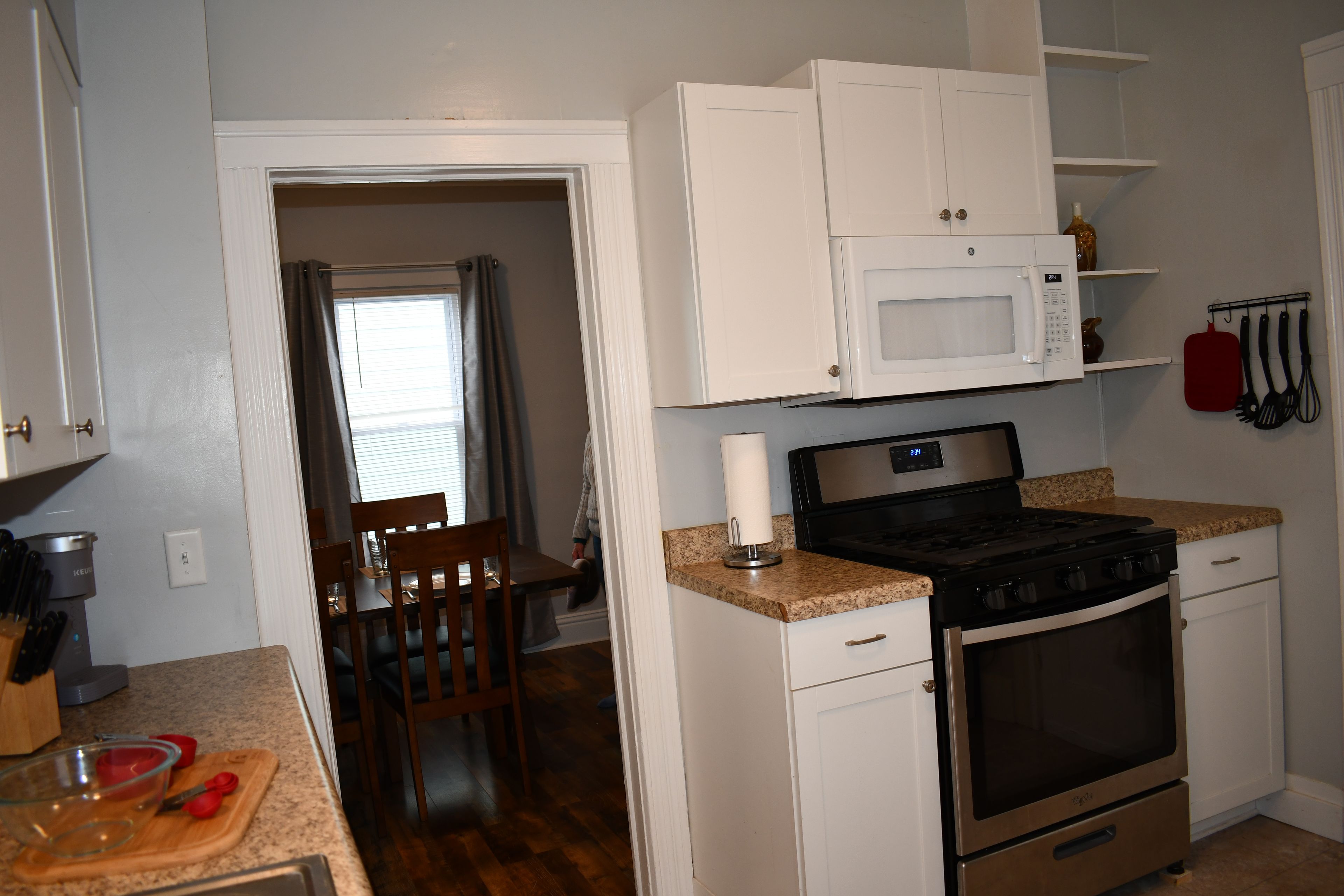 A compact kitchen with white cabinets, a microwave, a stove, and a sink.