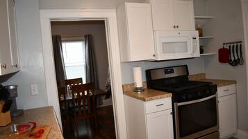 A compact kitchen with white cabinets, a microwave, a stove, and a sink.