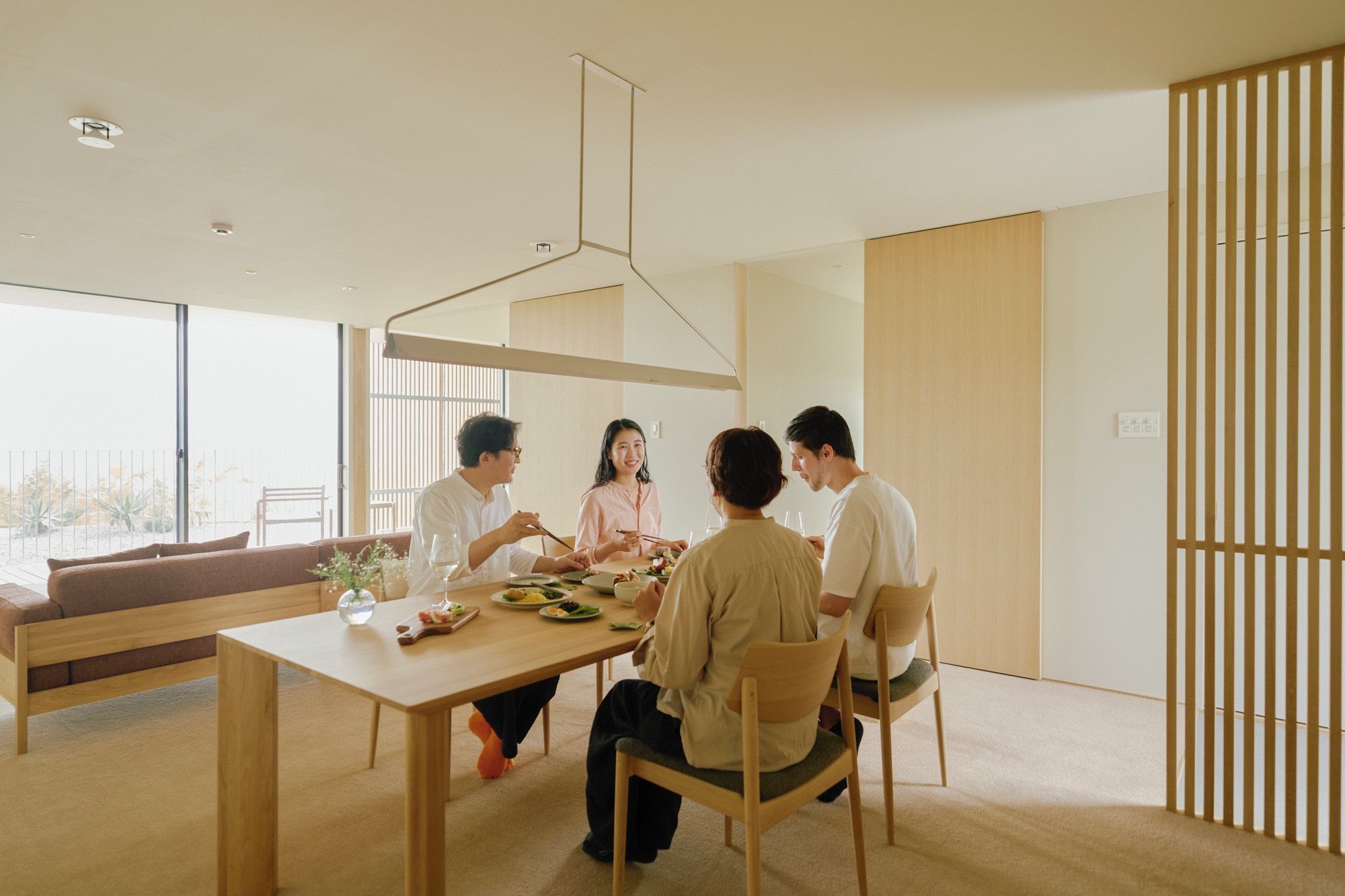 Un espace repas moderne avec une table en bois, des chaises et une grande fenêtre.