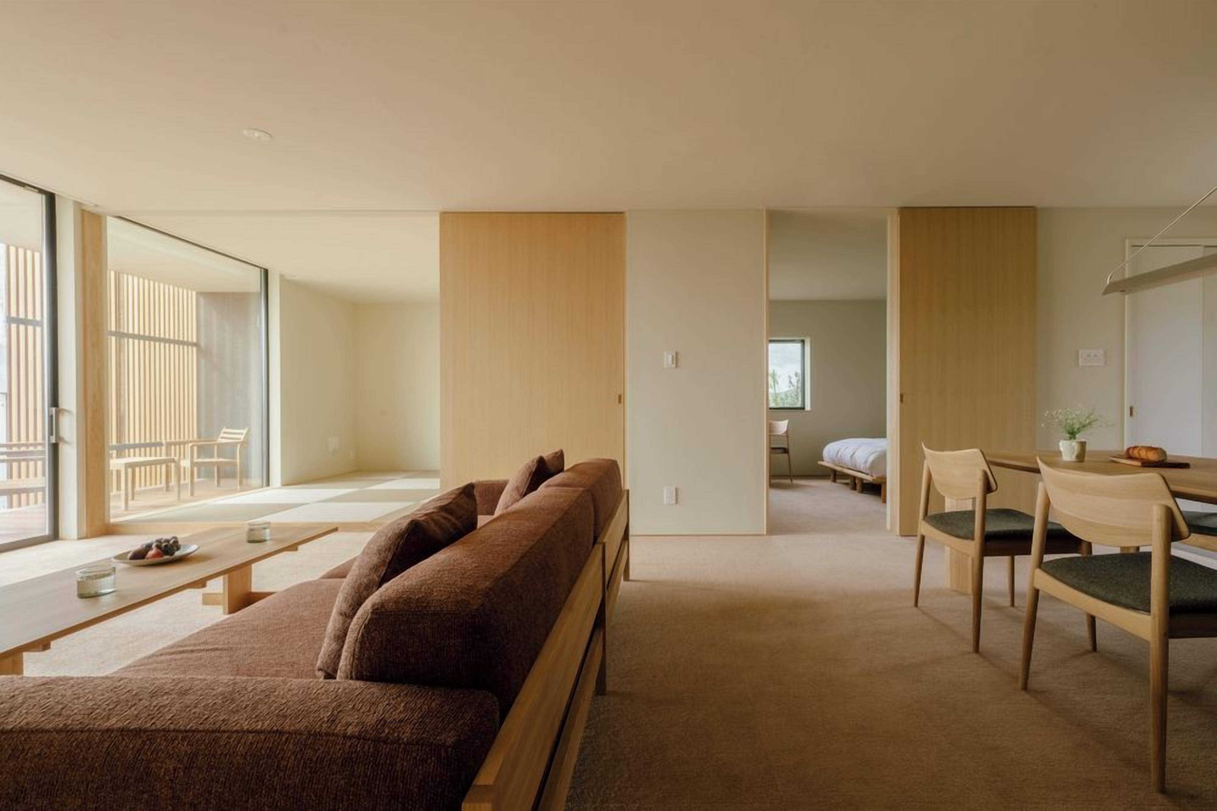 Una sala moderna con un sofá, una mesa de comedor con sillas y vistas a través de un ventanal.