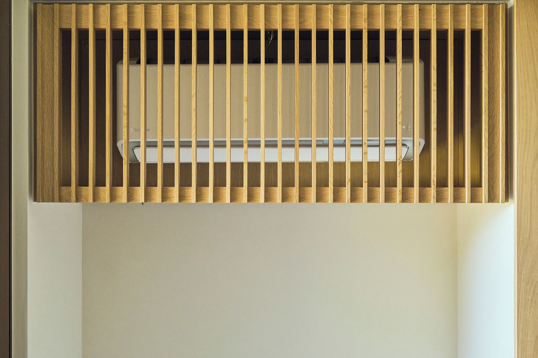 Une grille de ventilation au plafond, dotée de lames verticales et d’un luminaire central.