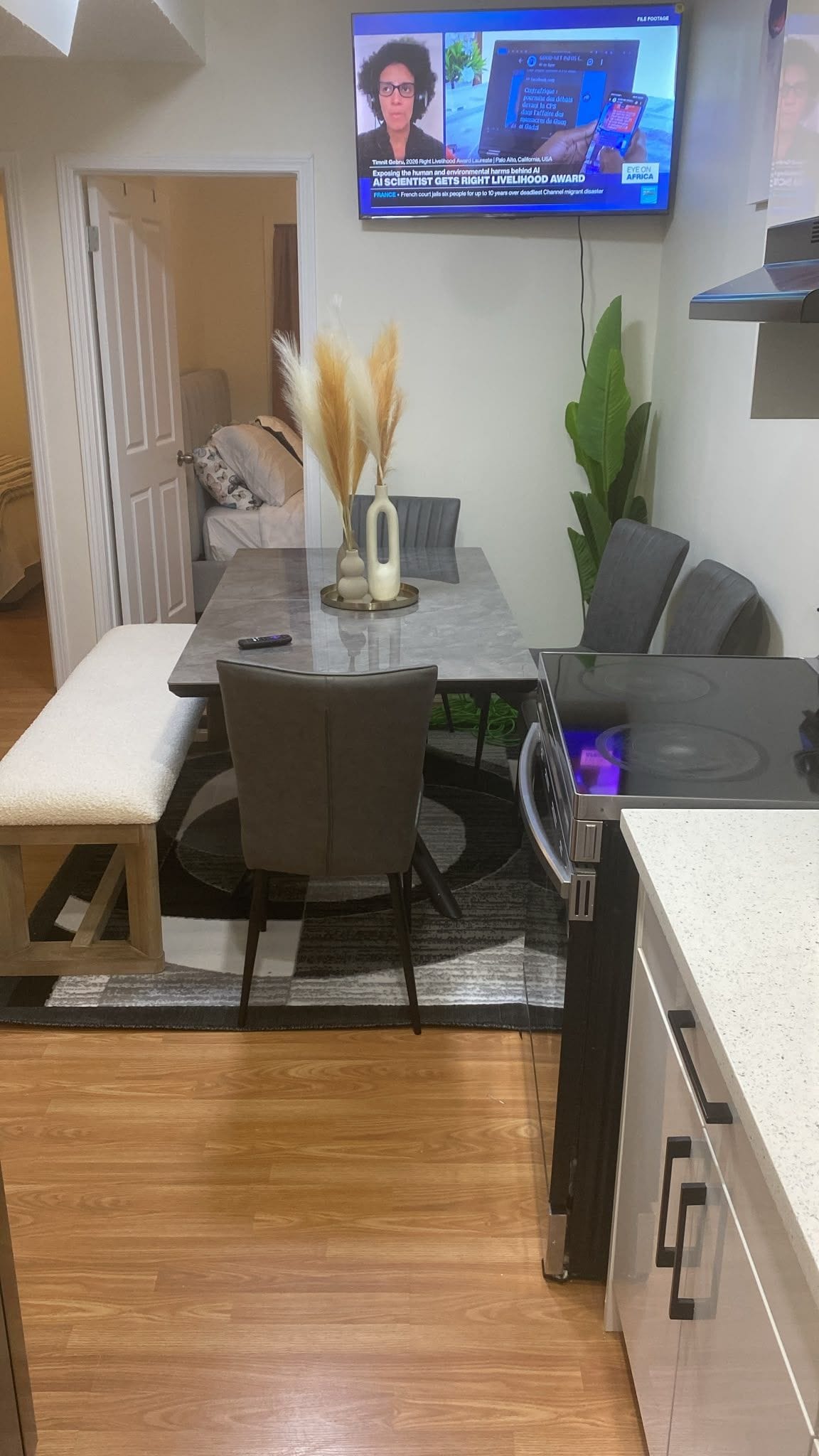 A modern dining area with a table, chairs, and a television mounted on the wall.