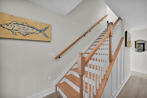 A staircase with wooden steps and white balusters, a painting of a fish on the wall, and a round mirror on the wall. - Peaceful Riverfront Retreat, Relax, Unwind & Enjoy the Water (Welaka)