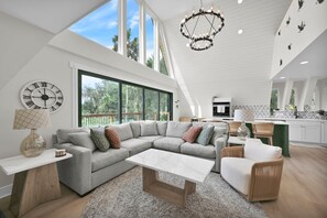 A spacious living area with a large sectional sofa, a coffee table, and a dining area with a kitchen in the background. - Peaceful Riverfront Retreat, Relax, Unwind & Enjoy the Water (Welaka)