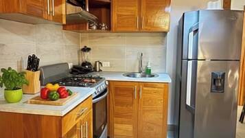 A kitchen with wooden cabinets, a gas stove, a sink, and a stainless steel refrigerator.
