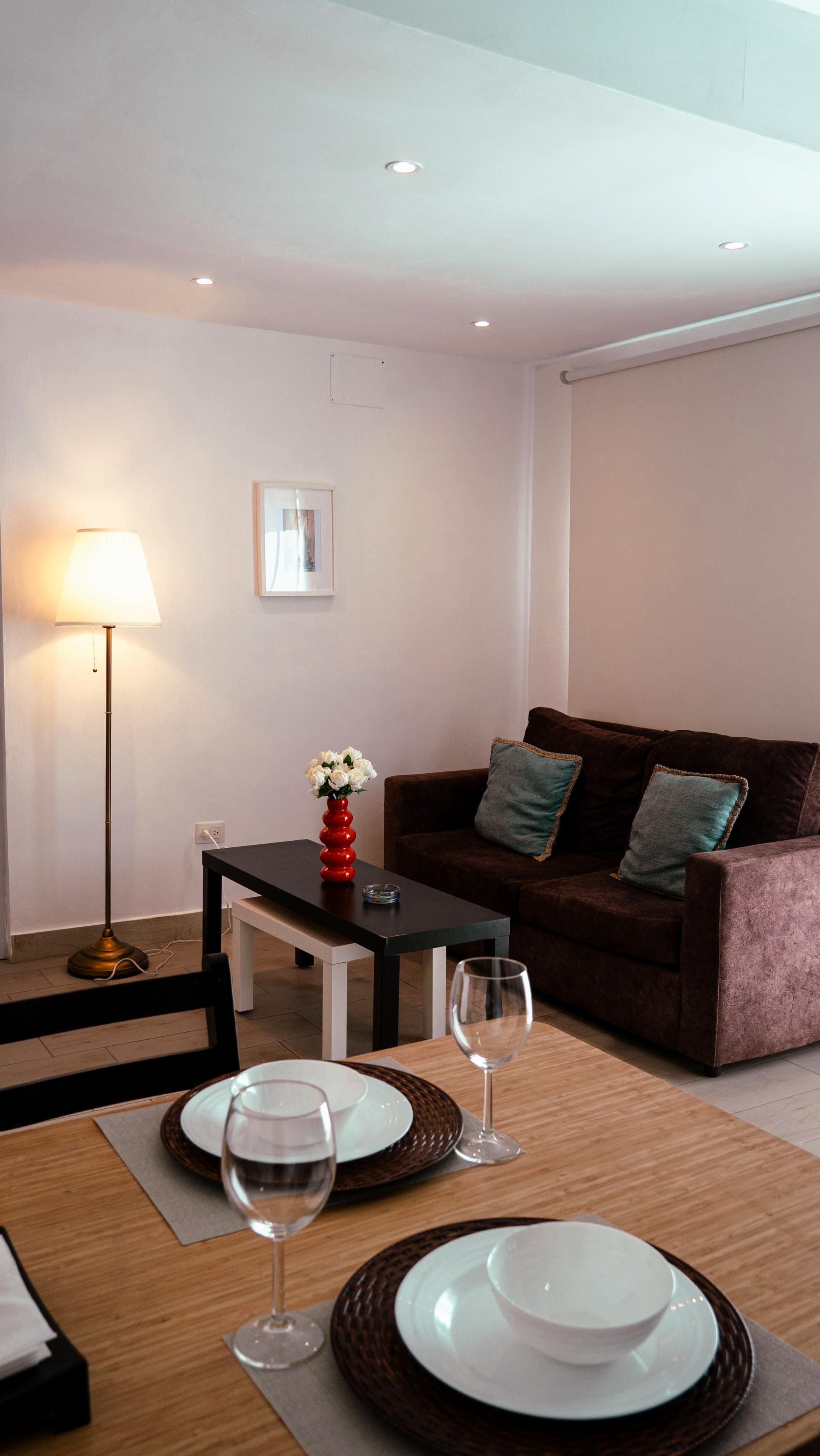 A modern living room with a sofa, a coffee table, and a dining table set for two.