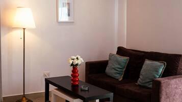 A modern living room with a sofa, a coffee table, and a dining table set for two.