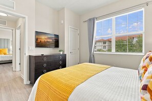 A bedroom with a bed, a dresser, a television, and a window with a view. - Stay Central Explore More Orlando 3BR Condo (Orlando)