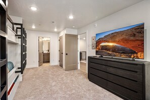 A modern interior with a large flat-screen TV mounted on a wall, a dark wooden dresser, and a carpeted floor. - Terra P-11, Private Spa, Community Amenities w/ Water Slide! (Hurricane)