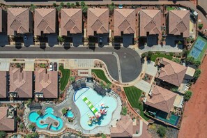 Vue aérienne d’un quartier résidentiel comprenant plusieurs maisons, une piscine et un court de tennis.