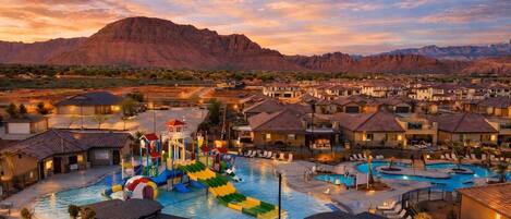 A resort with multiple swimming pools, a water park, and a mountainous backdrop.