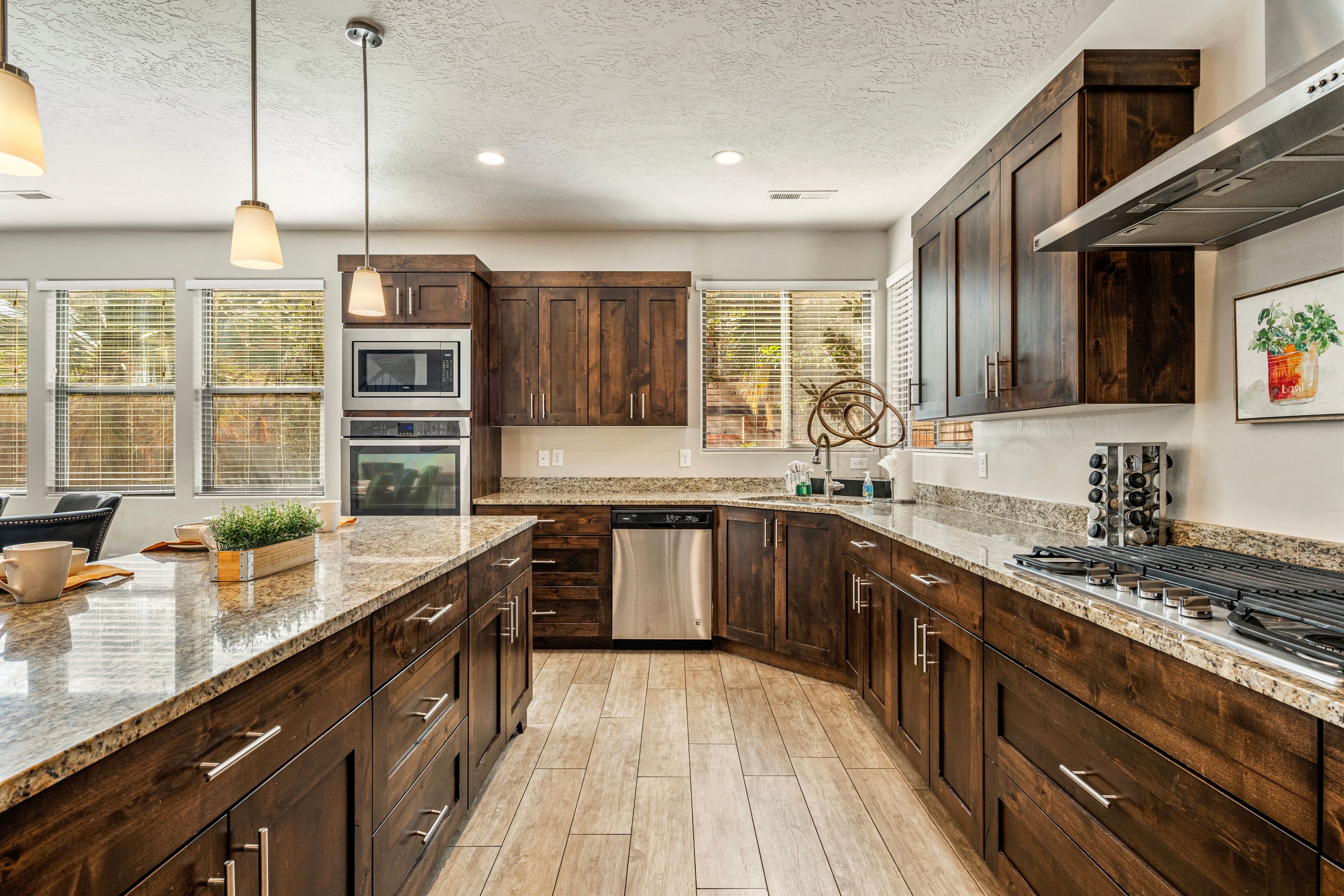 A modern kitchen with dark wood cabinets, stainless steel appliances, and a granite countertop.