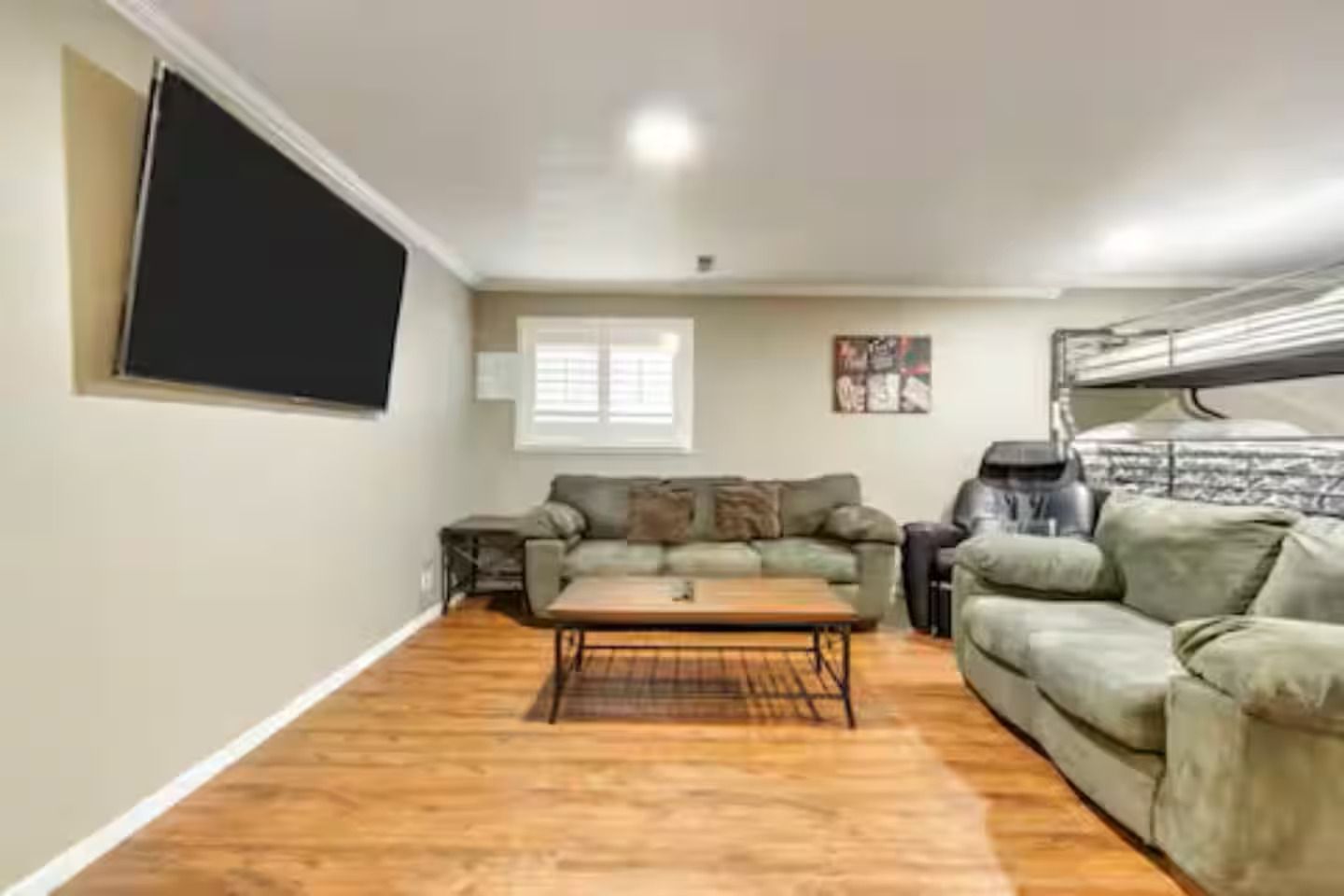 Una sala de estar con un sofá, una mesa de centro y un televisor montado en la pared.