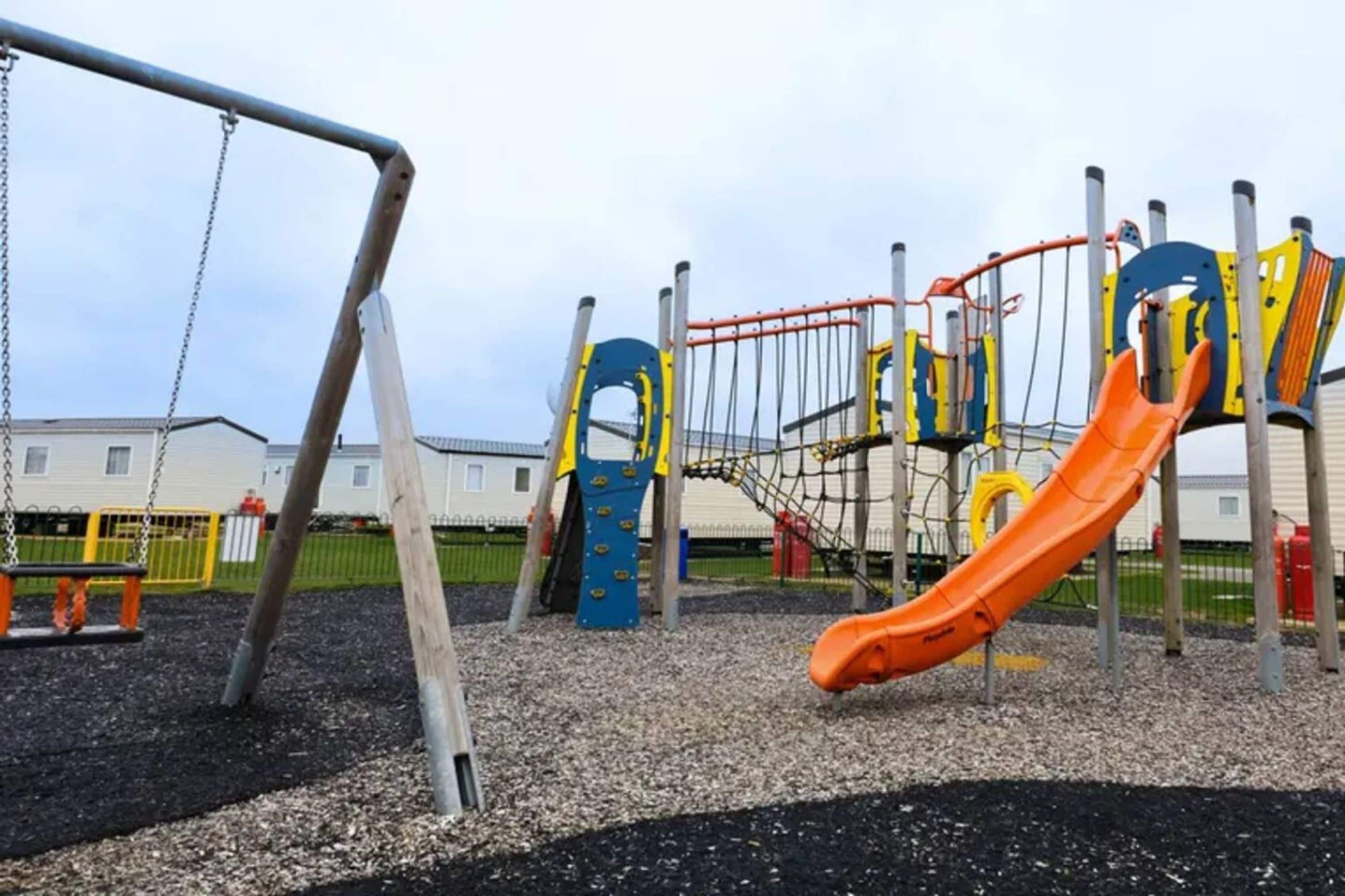 Ein Spielplatz mit Rutsche, Schaukeln und Klettergerüsten.