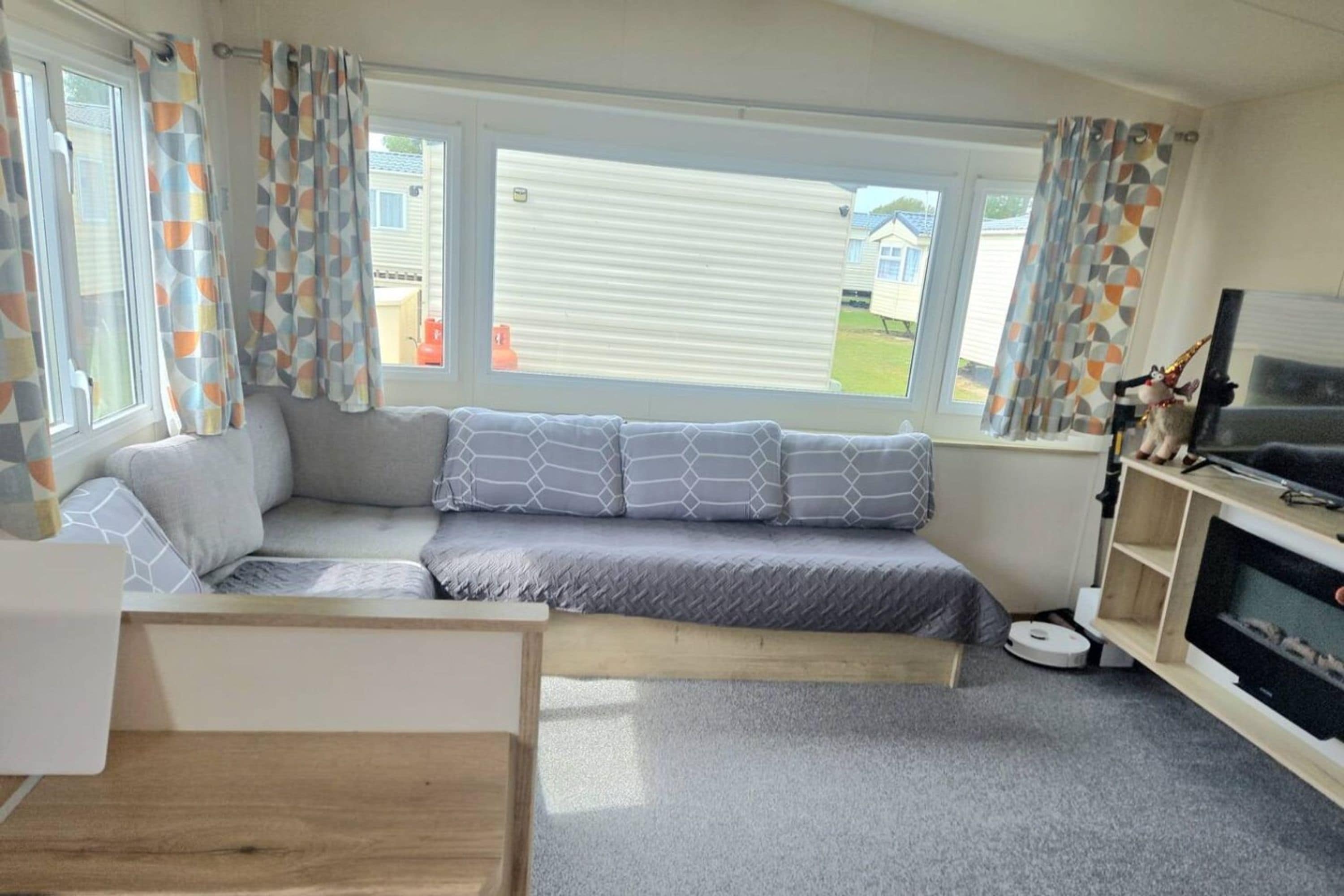 A modern living room with a sofa, a television, and a window with curtains.