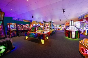 An indoor arcade with various gaming machines and a neon-lit pool table. - Located at New Beach Holiday Park in Dymchurch (Romney Marsh)