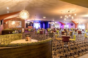 Un espace intérieur spacieux offrant différentes options d’aménagement, notamment un canapé incurvé, ainsi que plusieurs tables et chaises.