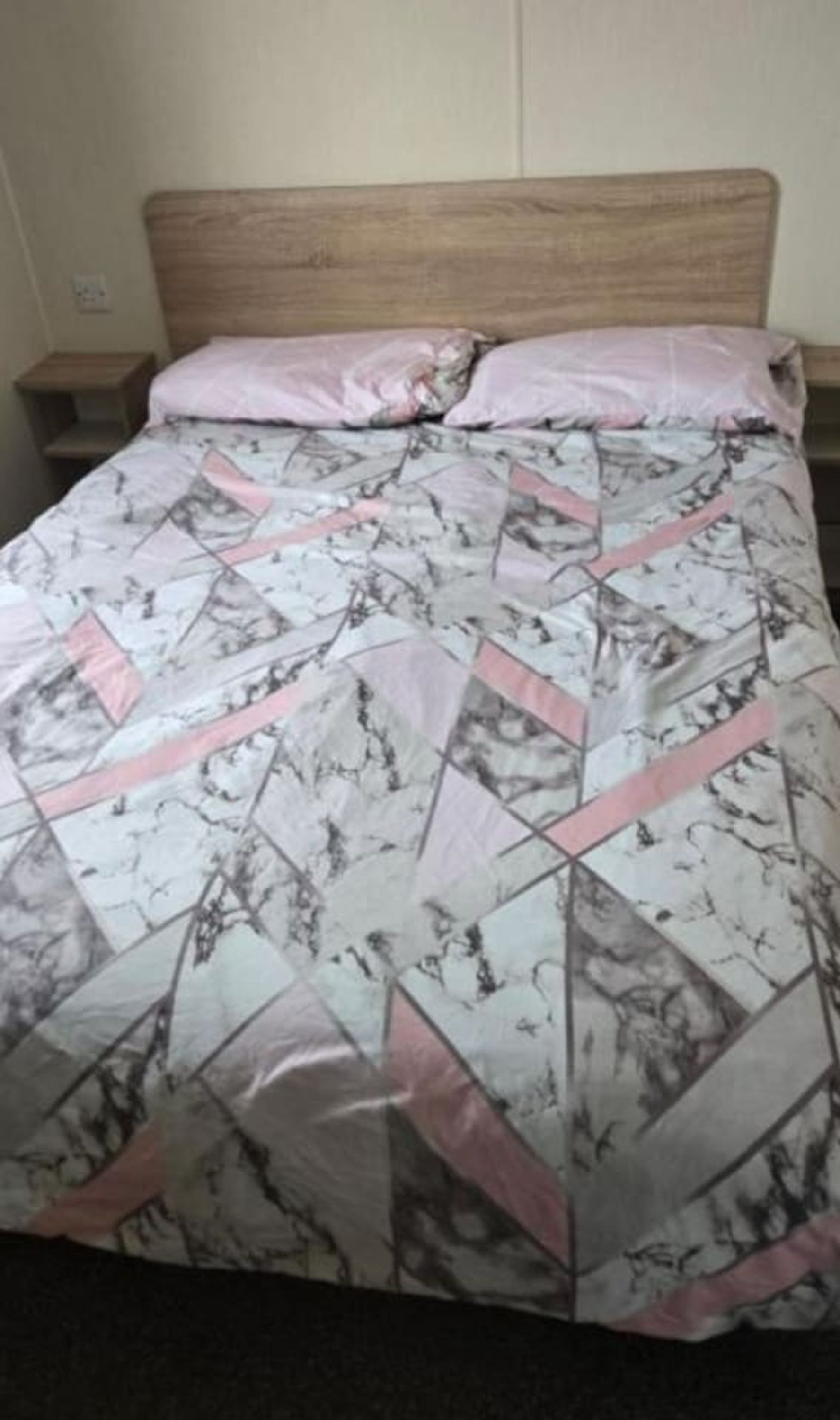 Een bed met een bedovertrek met een patroon en een houten hoofdbord.