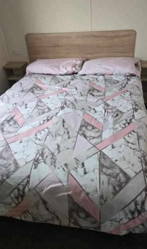 Un lit avec une couvre-lit à motifs et une tête de lit en bois.