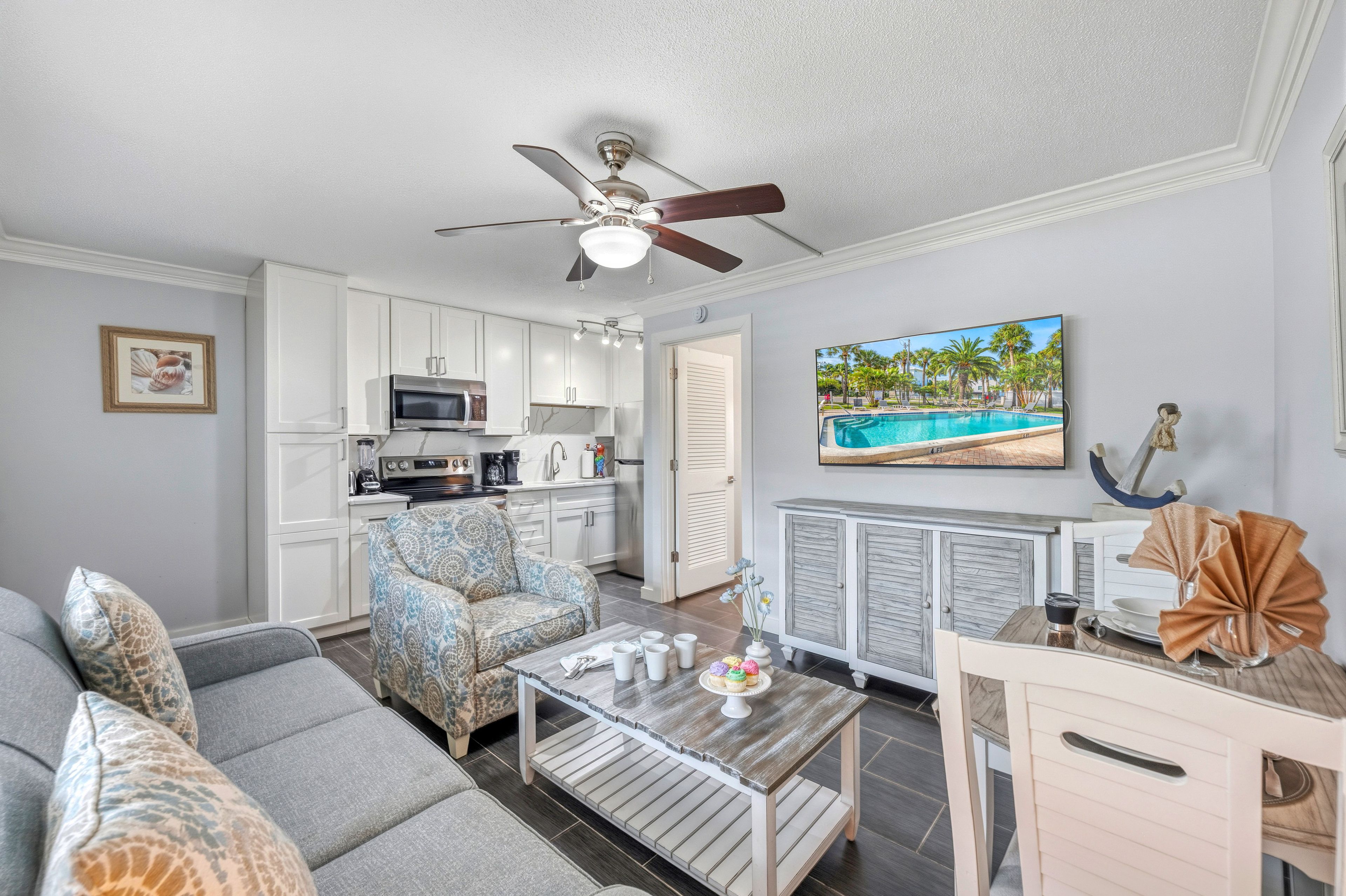 A modern living room with a sofa, a coffee table, and a television displaying a pool scene.