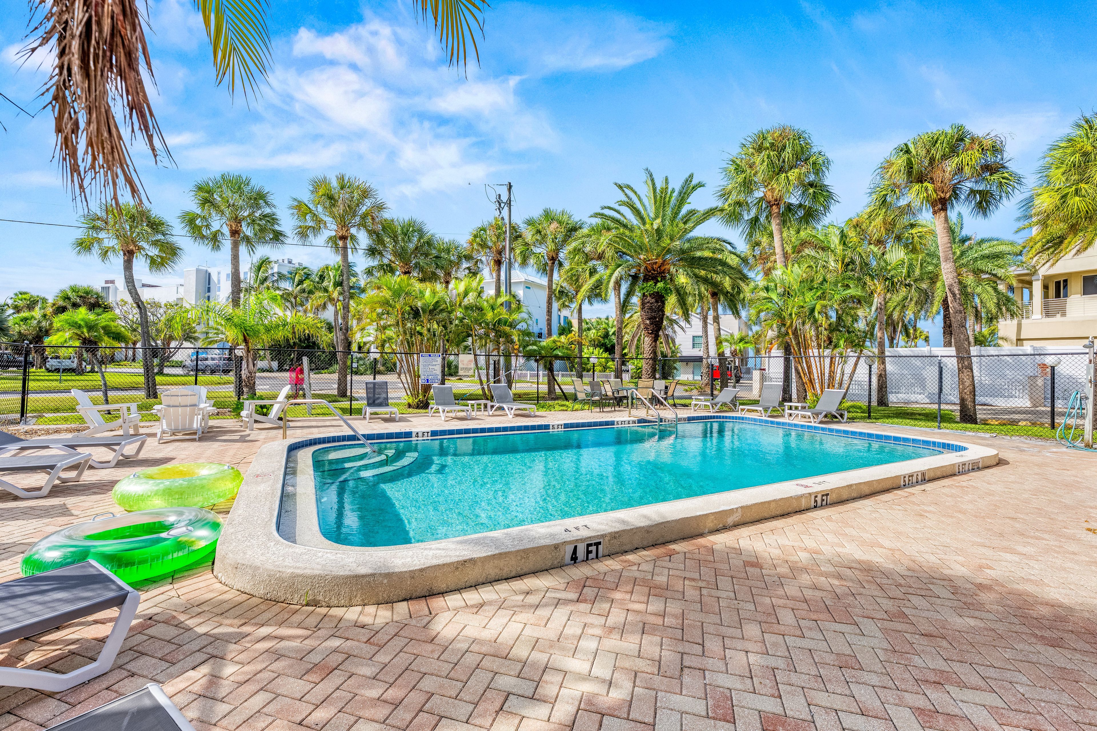 A swimming pool with lounge chairs and palm trees in the background.