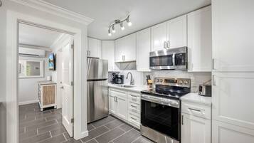 A modern kitchen with white cabinetry, stainless steel appliances, and a tiled floor.