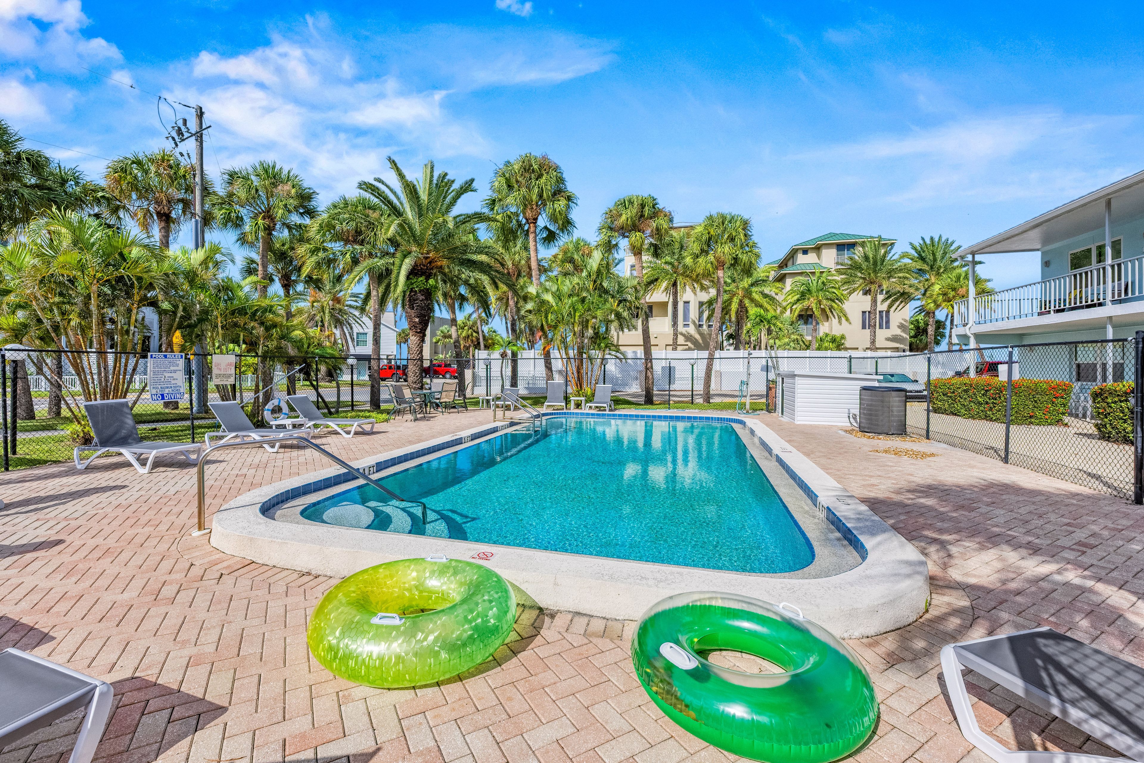 A swimming pool with lounge chairs and palm trees.
