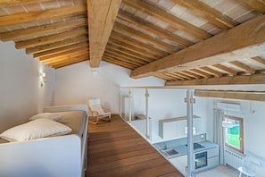 Une chambre avec un plafond en bois, un lit, une chaise et une vue sur un balcon.