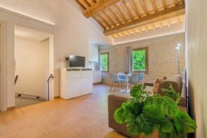 Un saló modern amb televisió plana, zona de menjador amb taula i cadires, i cuina amb armaris i taulell.