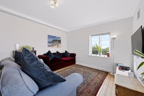 A living room with a red sofa, a blue sofa, and a patterned rug. - Serene 2 Bed 2 Bath Apt (London)