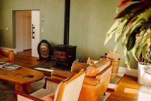 A cozy living room with a fireplace, leather sofas, a wooden coffee table, and a potted plant.